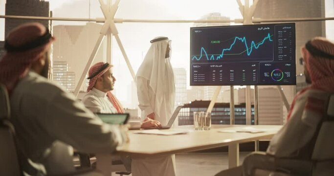 Modern Middle Eastern Business Office Meeting: Confident Arab Businessman Uses Interactive Display, Makes Report to a Group of Corporate Partners, Shows Statistics, Growth and Financial Analytics