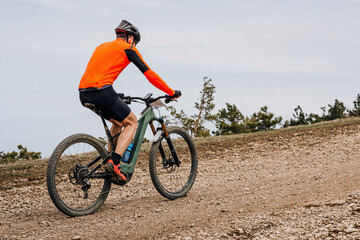 Fototapeta na wymiar male cyclist riding mountain bike uphill cross-country cycling, biking on gravel road