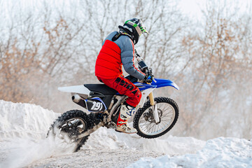 motocross rider riding winter off-road motorcycle racing, snow splashes from under rear wheel