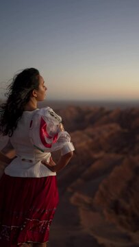 rear view young latin woman standing at the viewpoint over the valley of the moon at sunset looking at the horizon and desert landscape