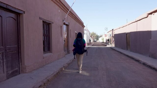 vista trasera mujer excursionista turista caminando con una mochila por las calles de San Pedro de Atacama
