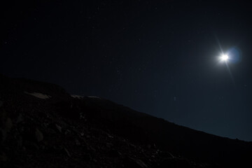 Rocky slope of Mount Ararat with patches of snow at night, against the background of the night sky with stars