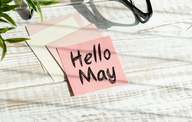 Hello May. text on white notepad paper on wooden background.