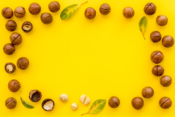 Pile of raw macadamia nuts with leaves. Healthy protein snack background