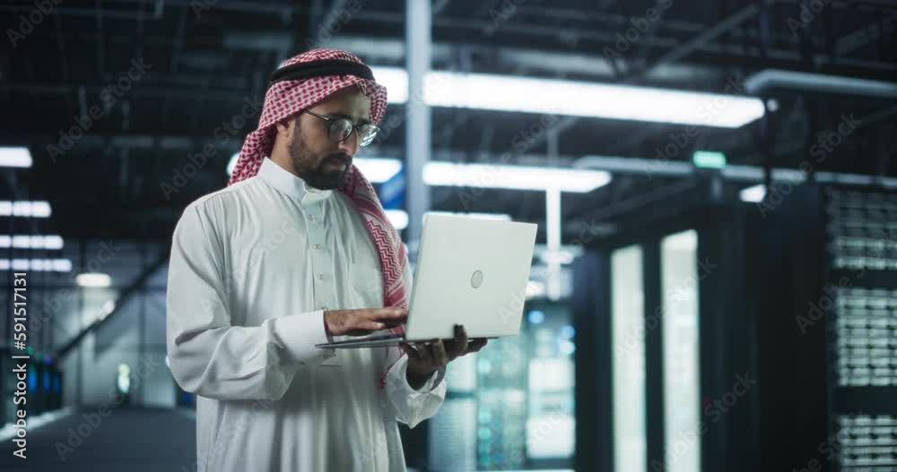 Poster Muslim Data Center IT Engineer Standing in a Room with Operational Server Racks. Cloud Computing Architect Uses Laptop Computer for Servicing the System in Cyber Security and Data Protection Facility