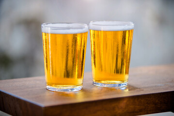 Two glasses of beer are on the bar
