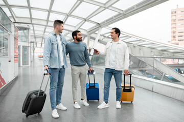 Fototapeta na wymiar Group Of Three Guys Standing With Travel Suitcases In Airport