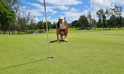 Beautiful female golfer successfully puts ball on field