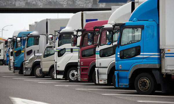 高速道路のサービスエリアの駐車場に並ぶ大型トラックの風景
