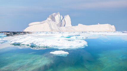 Melting icebergs by the coast of Greenland, on a beautiful summer day - Melting of a iceberg and pouring water into the sea - Greenland