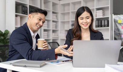 The couple of business employee working in the office with laptop and holding the coffee cup, happy, 