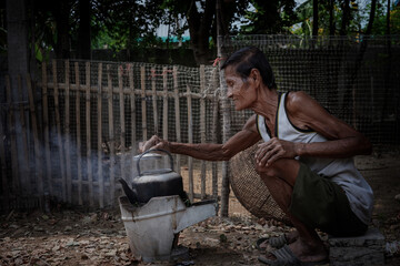 An Asian farmer who is a local resident, a poor elderly man is boiling herbal juice for the...