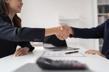 Young happy woman applying for job and giving she's CV to a manager during the interview and shakehand in the office. 