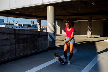 Multiracial teenage girl on skateboard in modern city during summer day.