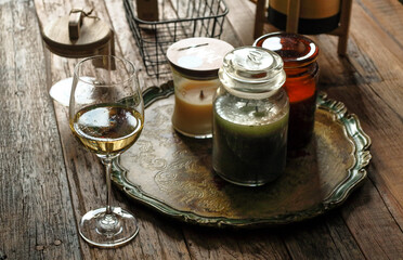 Kielich białego wina stojący na drewnianym stole obok świec zapachowych oświetlone słońcem .