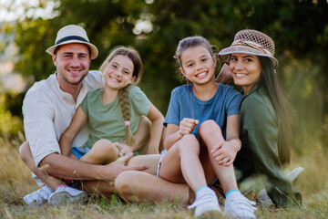 Happy family sitting on a medow, resting after hiking in nature.