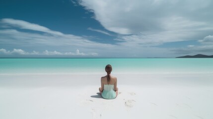 Fototapeta premium Young woman practicing yoga on white sand beach island by the sea. Harmony, meditation, healthy lifestyle and travel concept