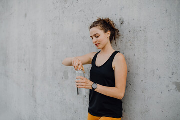 Young woman drinking water during jogging in city, healthy lifestyle and sport concept.