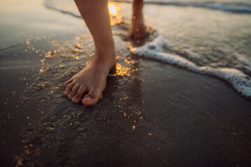 Woman walking on a beach during sunset, close-up of feet.