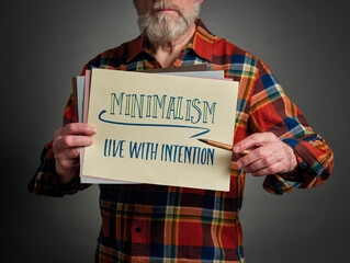 minimalism, live with intention - inspirational note held by a senior man, simplicity and lifestyle concept