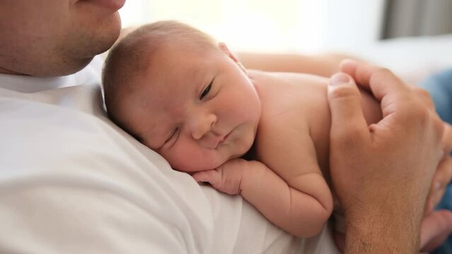 Adorable newborn baby lying at his father cheast and falling asleep. Beautiful moments of man parent and his infant child together