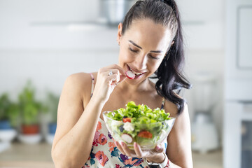 Healthy lifestyle young woman eating lettuce salad. Young brunette eating healthy food in her kitchen