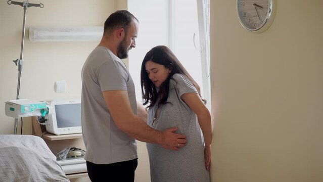 Young male supporting pregnant woman during contractions in hospital