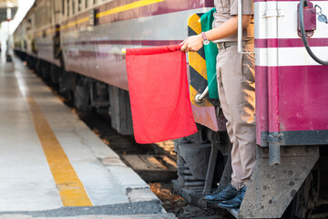 A train officer is showing the red flag for safety signal before the train is departure from platform. Transportation with people in action photo.