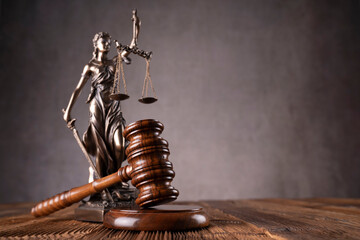 Law symbols composition. Gavel, scale and Themis sculpture on the rustic wooden desk. Gray...