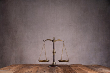 Law symbols composition. Gavel, scale and Themis sculpture on the rustic wooden desk. Gray...
