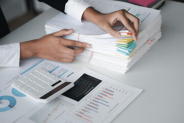 Businessman looking through stacks of papers on desk, corporate financial papers, monthly financial summary papers. Concept of document management in the organization.