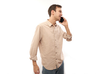 Fototapeta premium Portrait of young handsome caucasian man smiling and talking on mobile phone isolated on white studio background