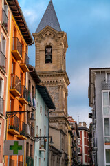 Fototapeta premium Pamplona, Navarra, SPAIN. The beautiful streets of the city of Pamplona. Beautifully coloured buildings with flowers of different colours, hanging from the balconies. Church tower in background. 