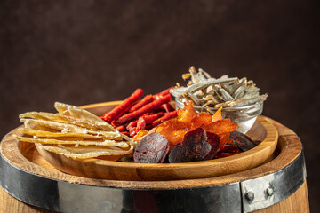 snacks for beer, Dried fish mix on wood plate. dried fish chorizo sausage meat carpaccio on a dark background. place for text, top view