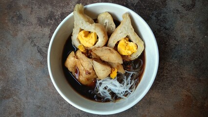 Pempek with vermicelli and cuko sauce on white bowl. Pempek, mpek-mpek or empek-empek is a savory Indonesian fishcake delicacy, made of fish and tapioca, from Palembang, South Sumatera, Indonesia.