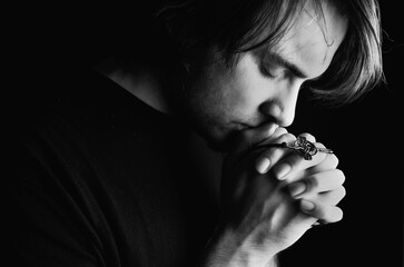 Young man praying with closed eyes