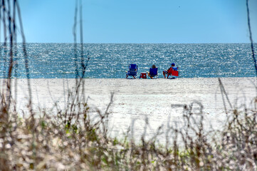 People relaxing on the beach on a beautiful spring day as seen from the dunes.