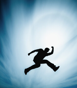 Man jumping against cloudy sky