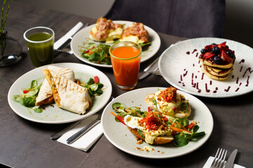 Brunch with four plates of meals - egg toast, burrito, american pancake and juices