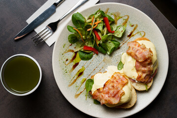 Top Down view of Toast with Egg, Cheese and Bacon on top and Salad on the side