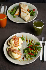 Toast with Egg, Cheese and Bacon on top and Salad on the side at the table