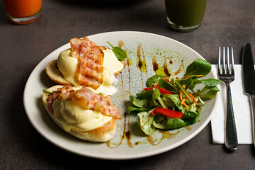 Toast with Egg, Cheese and Bacon on top and Salad on the side at the table