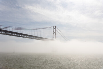 Suspension bridge shrouded in white fog over the sea