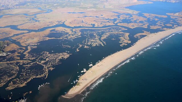 Drone video of İztuzu Beach in Dalyan, Muğla, featuring sandy coastline, azure waters, mountains, and a perfect vacation destination.