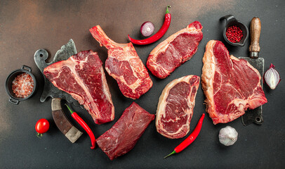 Variety of Raw Black Angus Prime meat steaks T-bone, tomahawk, New York steak. Set raw marbled beef strip loin steaks. place for text, top view