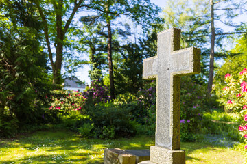 Kreuz auf einem Friedhof im Sonnenschein