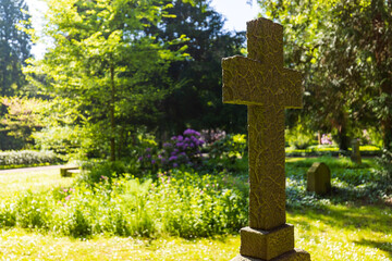 Kreuz auf einem Friedhof im Sonnenschein