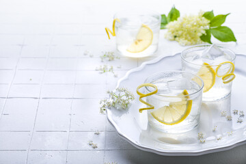 Obraz na płótnie Canvas Elderflower lemonade or gin sour with lemon and freshly picked elderberry flowers. Healthy refreshing mocktail with elderflower cordial syrup
