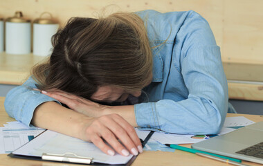 Tired woman in the office sleeping on the table, close-up. Lots of work, emotional burnout, stress