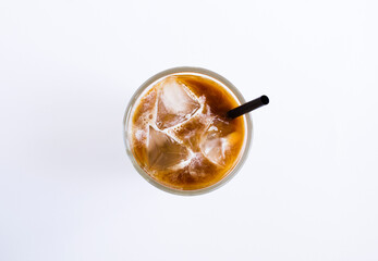 Iced coffee with milk in the drinking glass on the white background. Top view. Close-up.